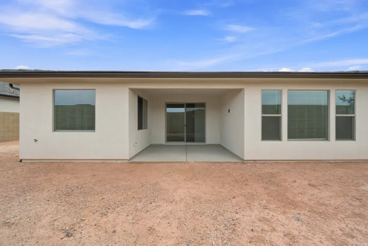 Stucco exterior with a covered patio, concrete slab, and sliding glass door access