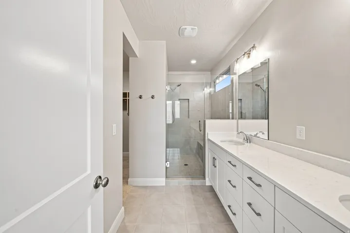 Double vanity with integrated sinks, white cabinetry, and polished chrome hardware