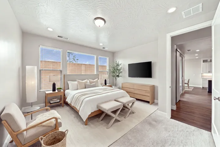 Recessed lighting, central ceiling fixture, multiple windows with blinds, carpeted flooring, wood-finish flooring in adjacent space