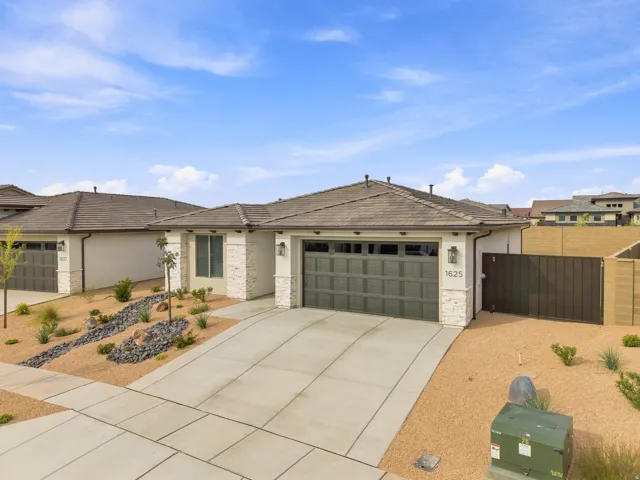 Single-story residence featuring a tile roof, an attached two-car garage, stone facade accents, and a concrete driveway
