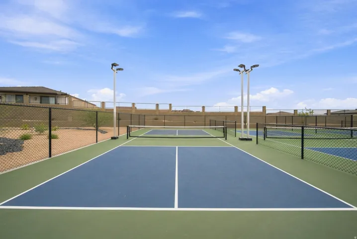 Multiple pickleball courts with perimeter fencing and overhead lighting