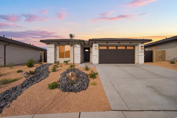 Modern home with a dark wood-finish garage door, white exterior, and stone accents