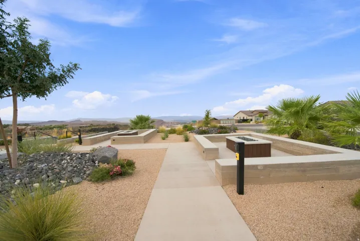 Outdoor living area featuring a built-in fire pit, integrated seating, and a concrete pathway