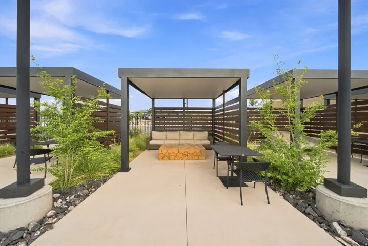 Multiple outdoor pergolas with slatted privacy screens and concrete bases