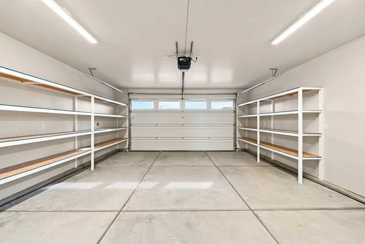 Spacious garage featuring a concrete floor, overhead lighting, and built-in shelving units