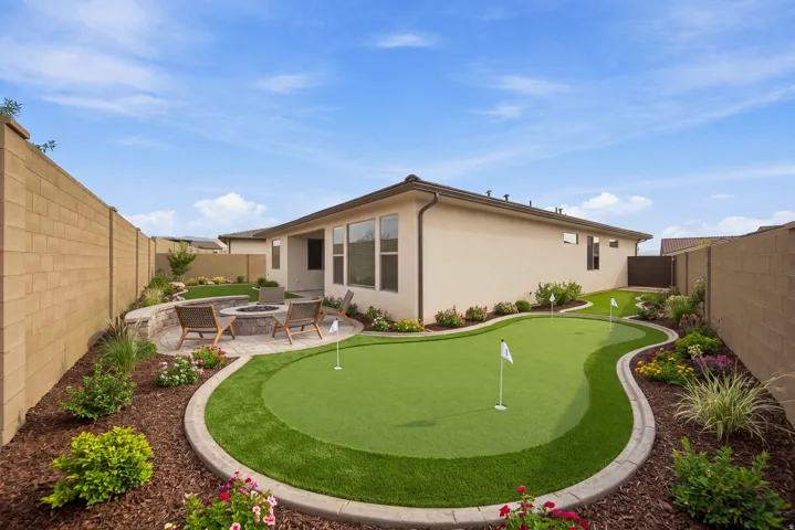 Backyard putting green with surrounding artificial turf and decorative landscaping