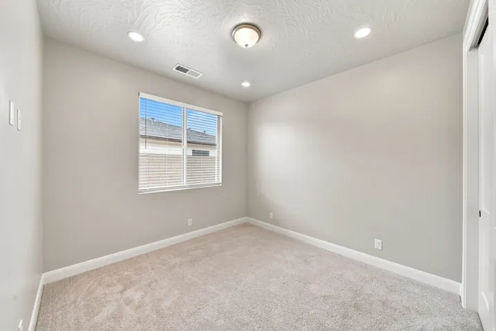 Neutral paint palette, recessed ceiling lighting, light-colored carpet, window with blinds, and white trim