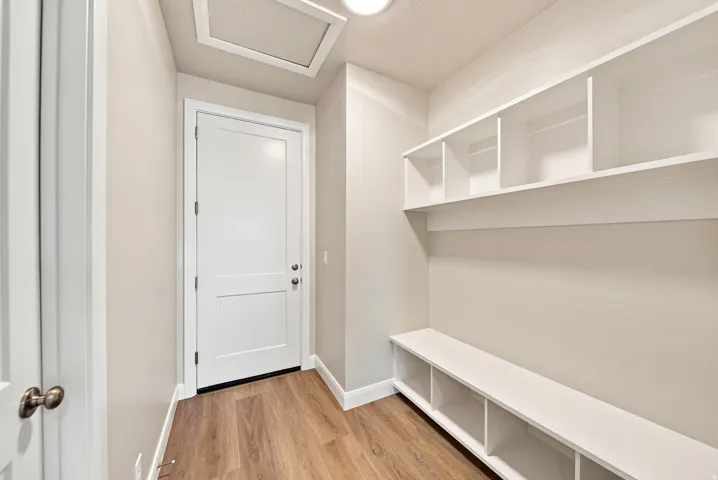 Built-in shelving with cubbies, built-in bench seating, wood-finish flooring, two-panel interior door, and recessed lighting