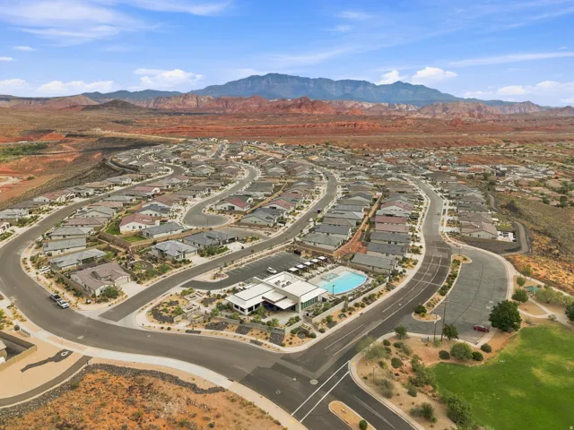 Expansive residential community with curved roadways, a central clubhouse, an outdoor swimming pool, and a large parking area