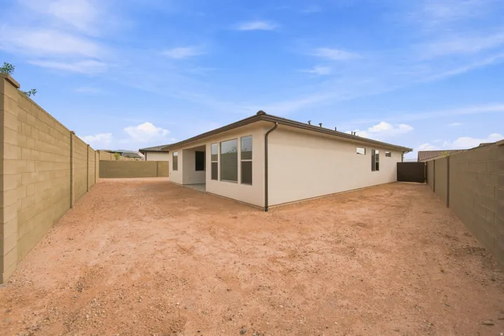 Expansive backyard with a stucco exterior, multiple windows, and a privacy fence