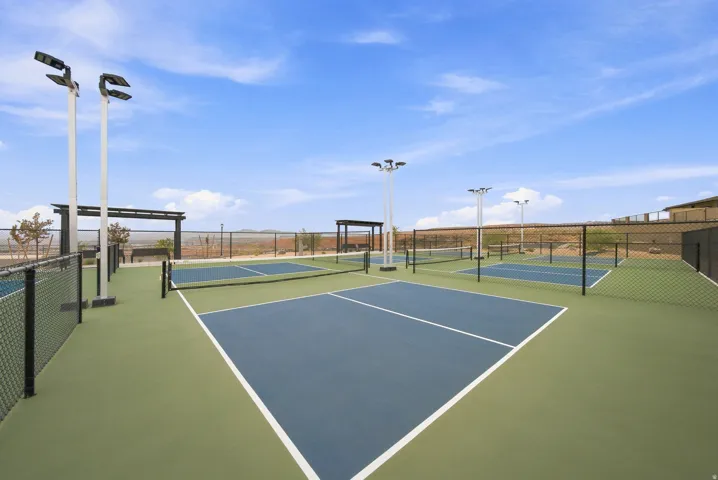 Multiple pickleball courts with perimeter fencing, floodlights, and shaded seating areas