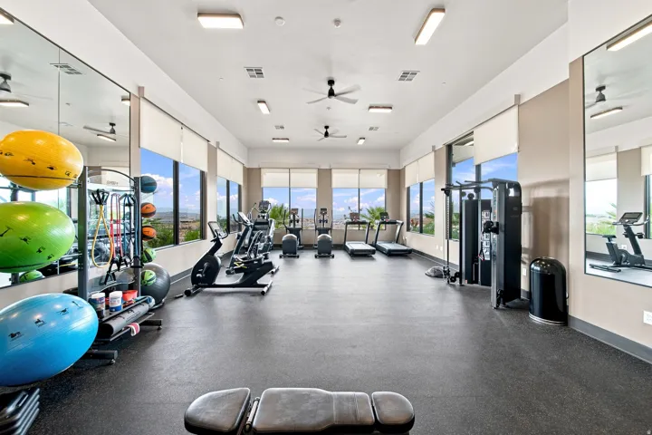 Spacious fitness center featuring rubber flooring, expansive windows, multiple ceiling fans, recessed lighting, and mirrored walls