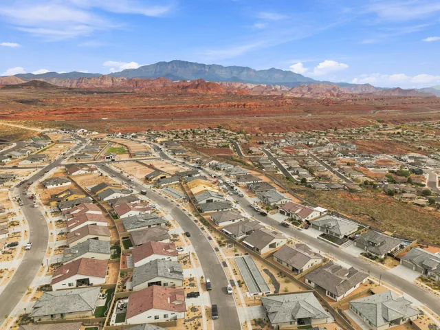 Expansive residential development featuring numerous single-story homes, paved streets, and a desert landscape backdrop