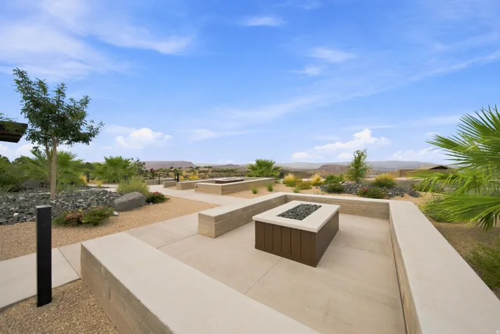 Expansive hardscaped patio featuring multiple built-in fire pits, integrated bench seating, and decorative landscaping