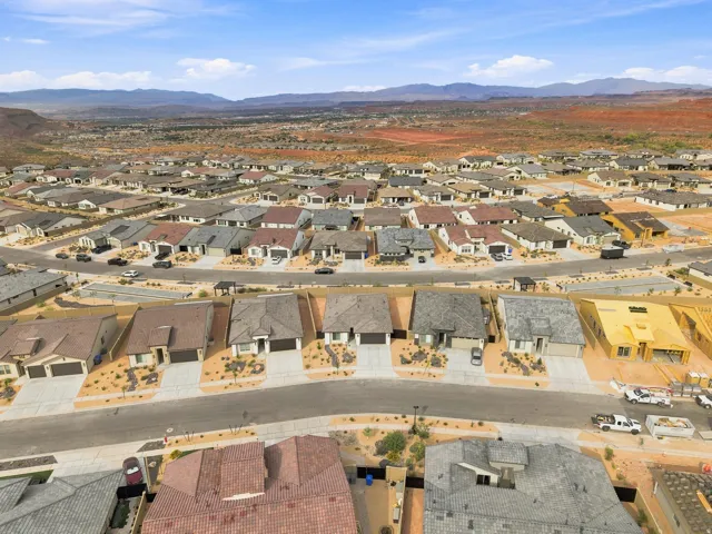 Expansive residential community with varied roof styles, desert landscaping, and mountain backdrop