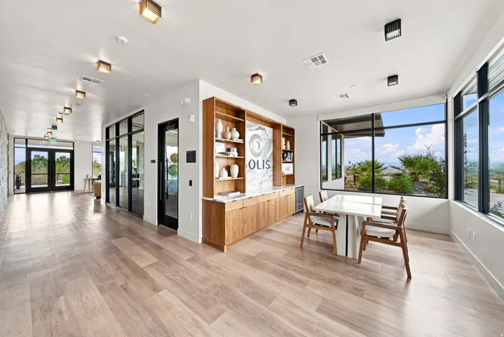 Expansive interior featuring wood-finish flooring, full-height windows, a built-in cabinetry unit, and recessed lighting