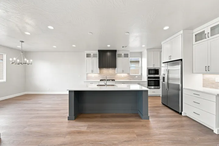 Open-concept kitchen featuring white cabinetry, a dark gray island with white countertop, and stainless steel appliances