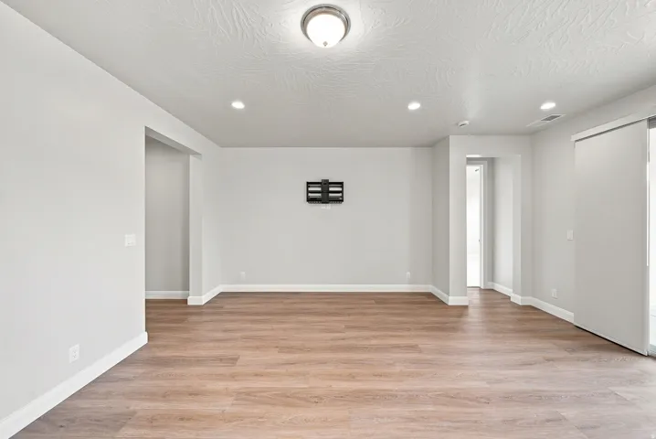 Spacious interior with wood-finish flooring, recessed lighting, and a ceiling-mounted light fixture