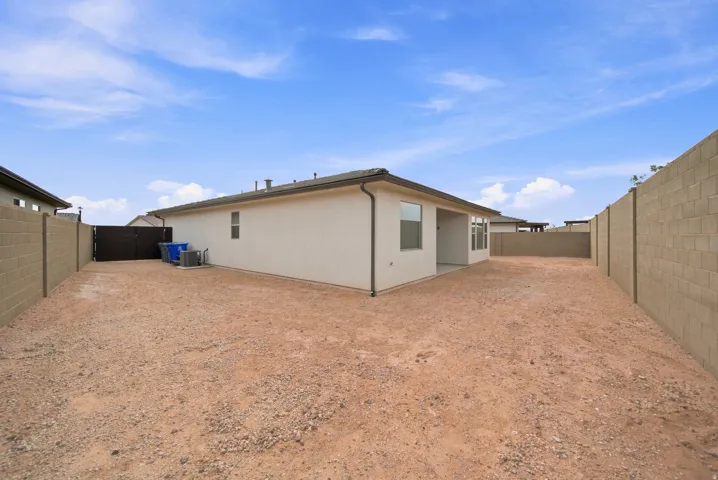 Expansive backyard featuring a stucco exterior, a block wall perimeter, and a covered patio area