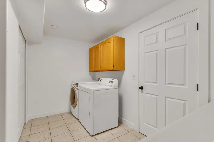Laundry area featuring tile flooring and overhead cabinetry