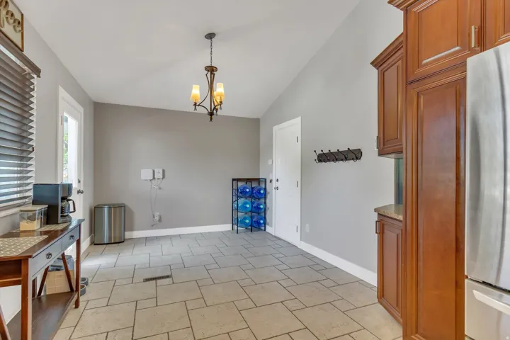 Vaulted ceiling with an ornate chandelier, tile flooring, wood-finish cabinetry, and a built-in countertop