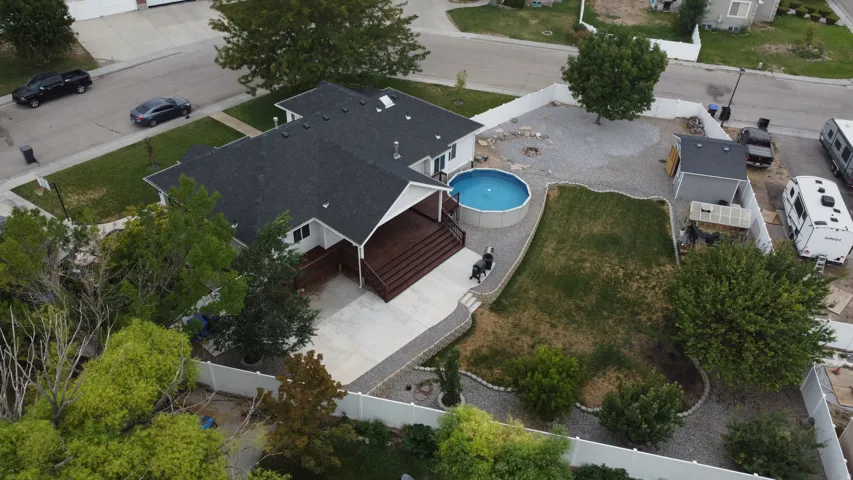 Expansive backyard featuring a manicured lawn, a gravel patio with a fire pit, and a swimming pool