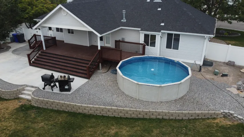 Multi-level deck with dark wood-finish flooring and railings, a concrete patio, and a retaining wall