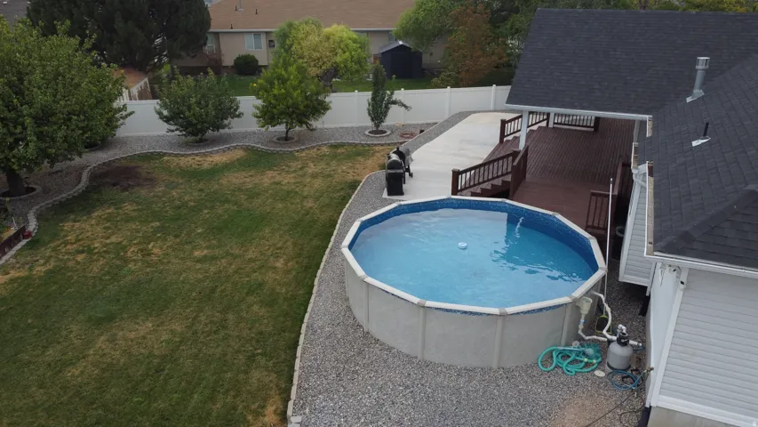Expansive backyard featuring an above-ground pool, a multi-level wood deck, a concrete patio, and a white privacy fence