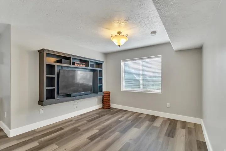 Built-in media center, wood-finish flooring, recessed lighting, window with blinds, and ceiling-mounted light fixture