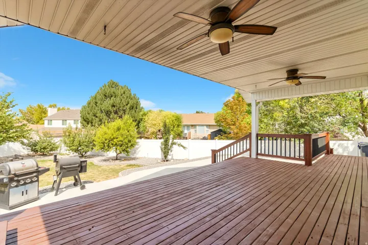 Expansive composite deck with rich wood-finish flooring, ceiling fans, and a covered pergola structure