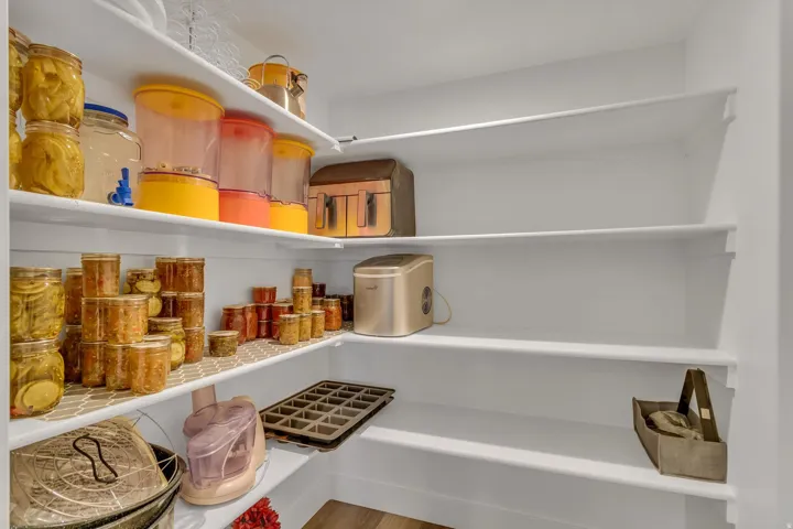 Built-in pantry shelving system with white finishes and wood-finish flooring