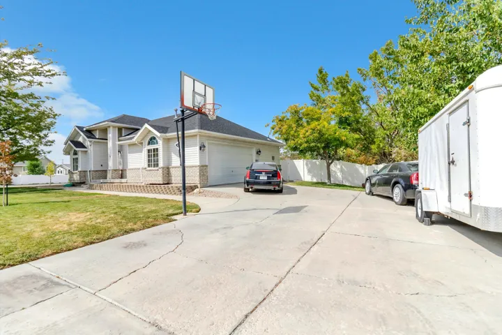 Expansive concrete driveway, attached garage, and stone-accented exterior