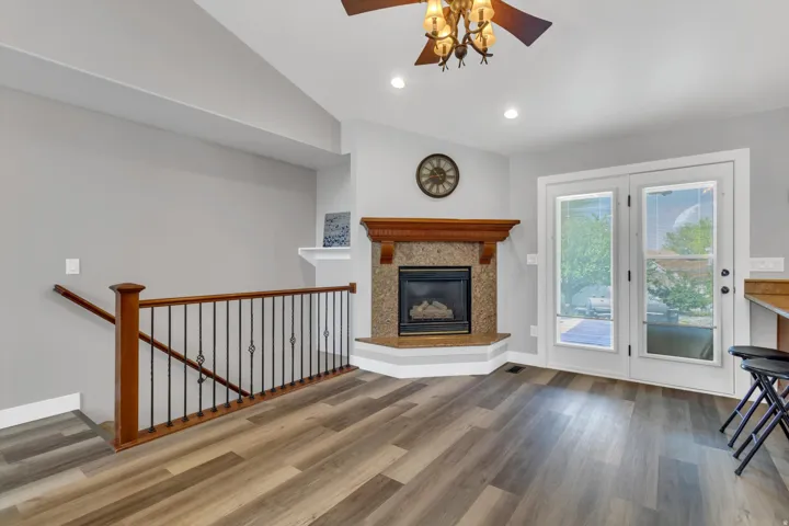 Wood-finish flooring throughout, featuring a corner fireplace with a decorative mantel and stone surround