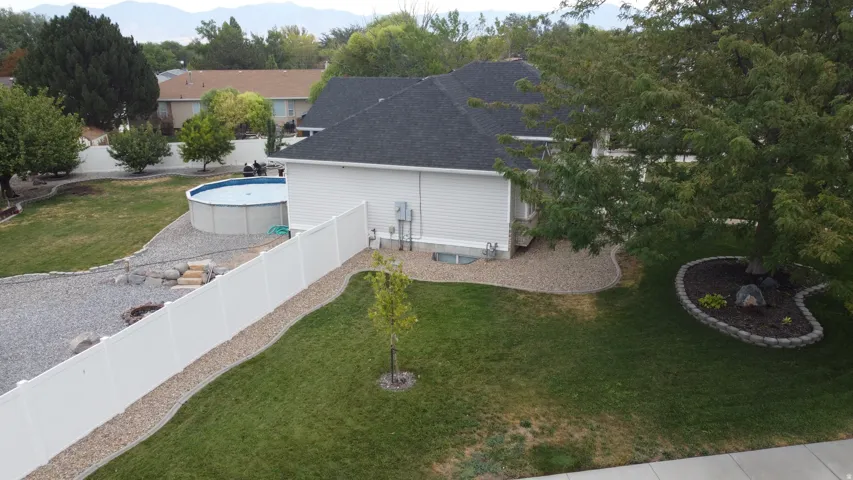 Expansive backyard featuring a manicured lawn, established trees, and a white privacy fence