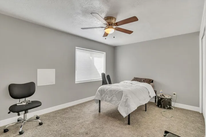 Neutral gray walls with white trim, a ceiling fan with integrated lighting, and a single window with blinds