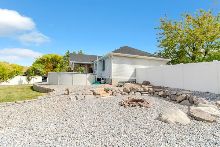 Expansive backyard featuring a gravel rock bed, an above-ground pool, a covered patio, and a privacy fence