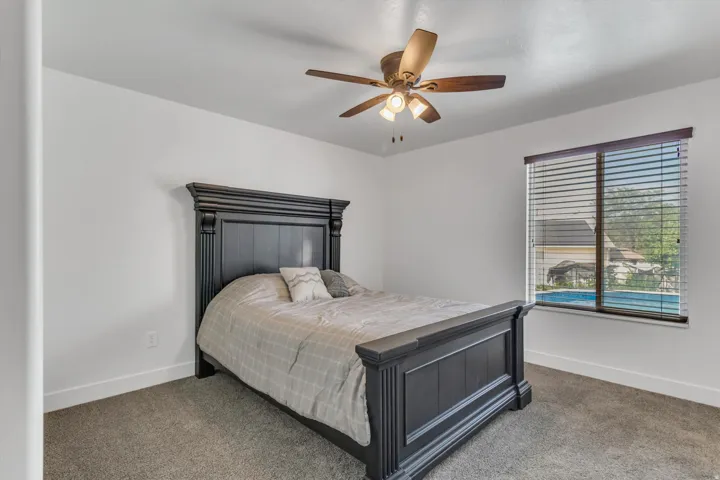Carpeted flooring, white walls, ceiling fan with integrated lighting, and a window with horizontal blinds