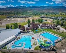 Large recreational pool, lap pool, water slides, and community building with a metal roof