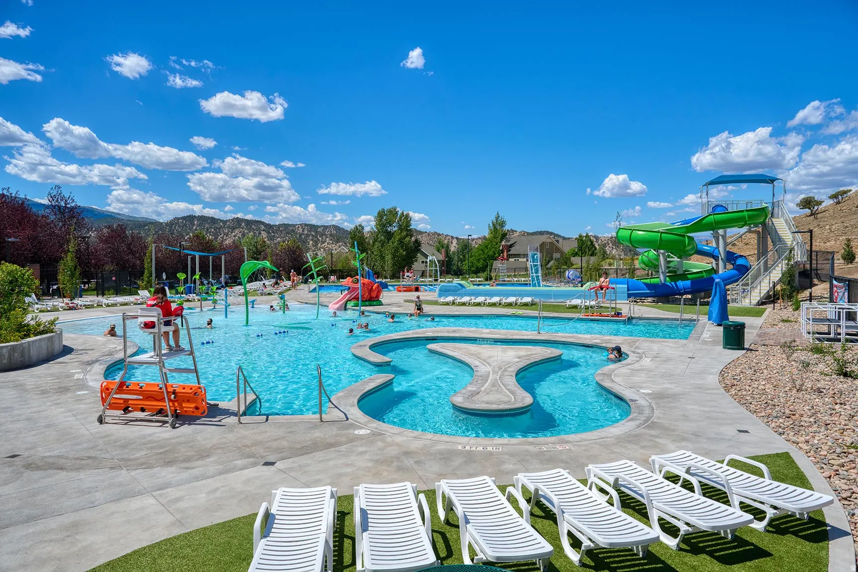 Expansive aquatic center featuring multiple pools, a water play structure, and two water slides