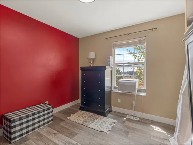 Wood-finish flooring with white trim, a single window, and a light-colored ceiling