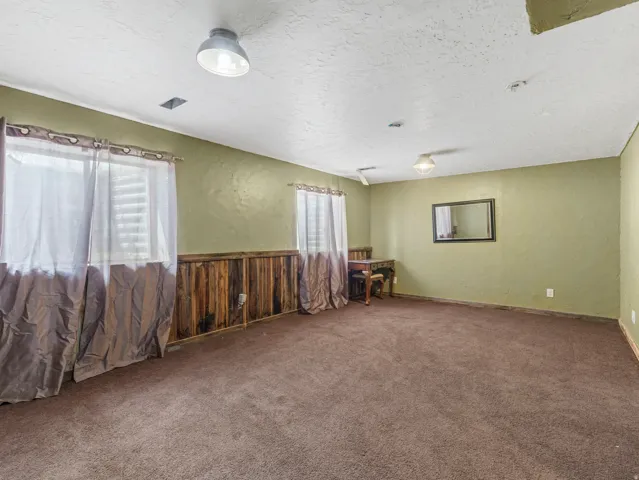 Spacious room featuring soft green walls, recessed ceiling lighting, and neutral carpet flooring
