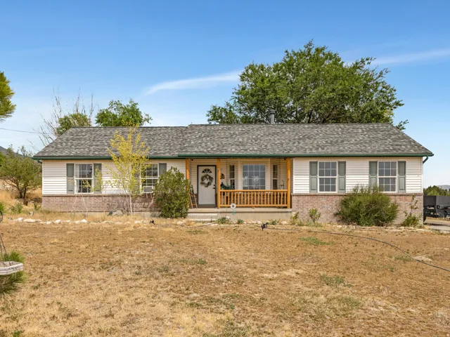 Charming ranch-style home featuring a brick and vinyl exterior, covered front porch with wooden railings, and multiple windows offering natural light throughout