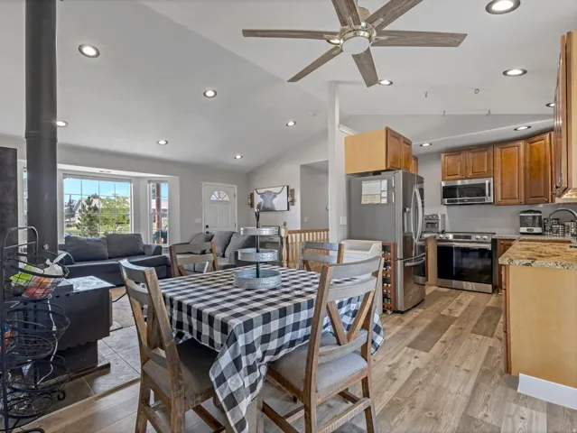 Vaulted ceiling with recessed lighting, wood-finish flooring, stainless steel appliances, wood cabinetry, and a bay window