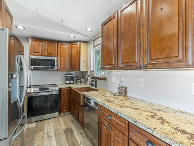 Warm wood cabinetry with detailed panel doors and brushed metal hardware frames this updated kitchen, anchored by a large granite-topped island with seating space
