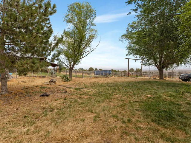Expansive outdoor area with mature trees and a partial wood fence
