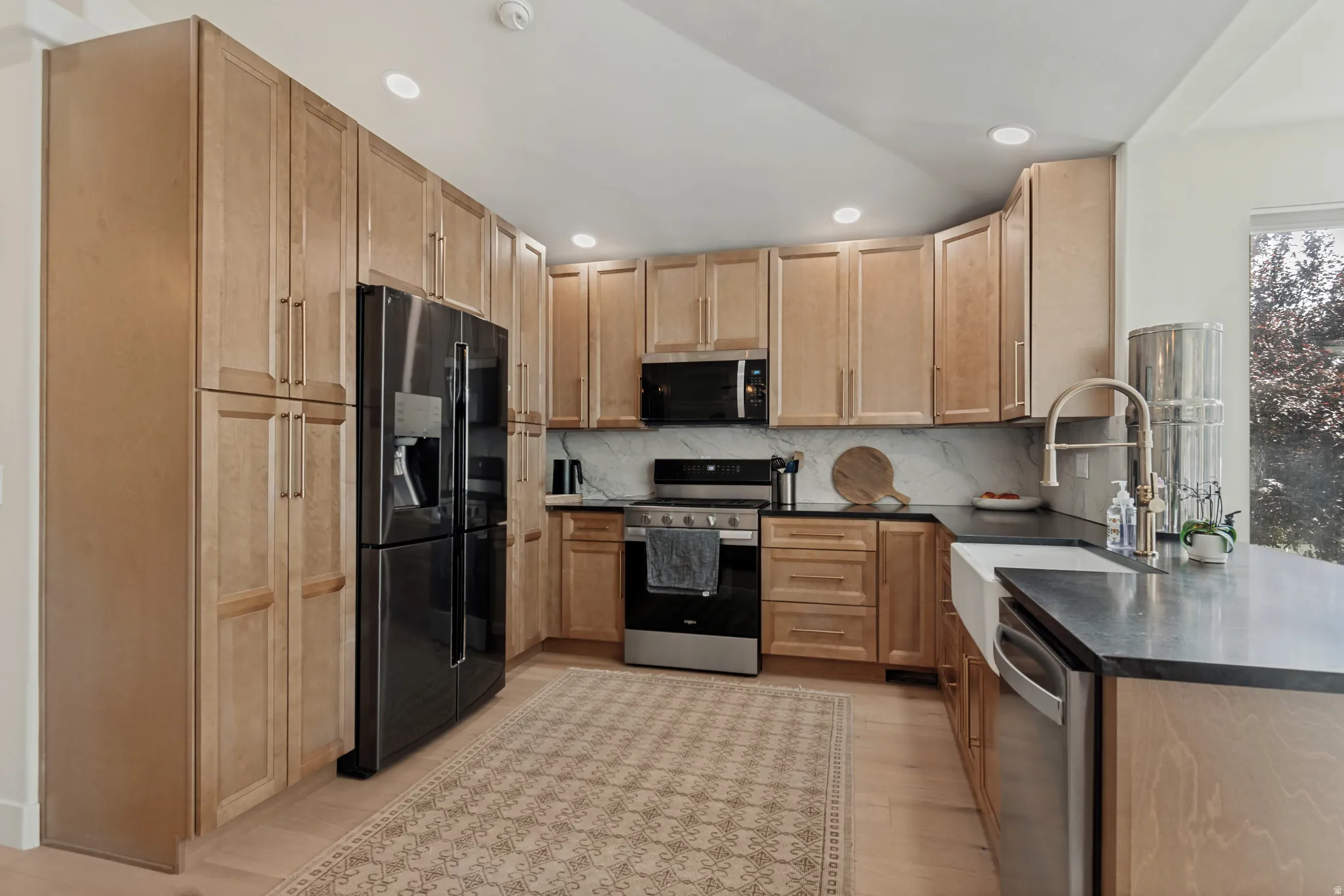 Spacious kitchen featuring warm wood cabinetry, stainless steel appliances including a French-door refrigerator and convection range, quartz countertops, an oversized island with seating, and recessed lighting throughout