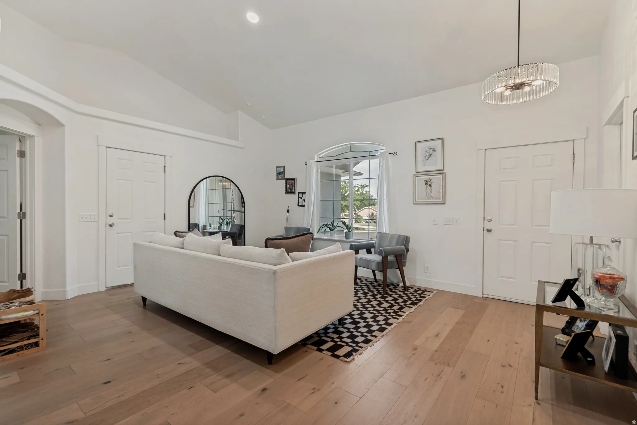 Bright, open-concept living space featuring hardwood flooring throughout, a neutral upholstered sectional sofa, and a modern pendant light fixture