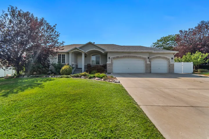Welcoming ranch-style home featuring a curved roofline and columned front entry, situated on a manicured lawn with mature landscaping