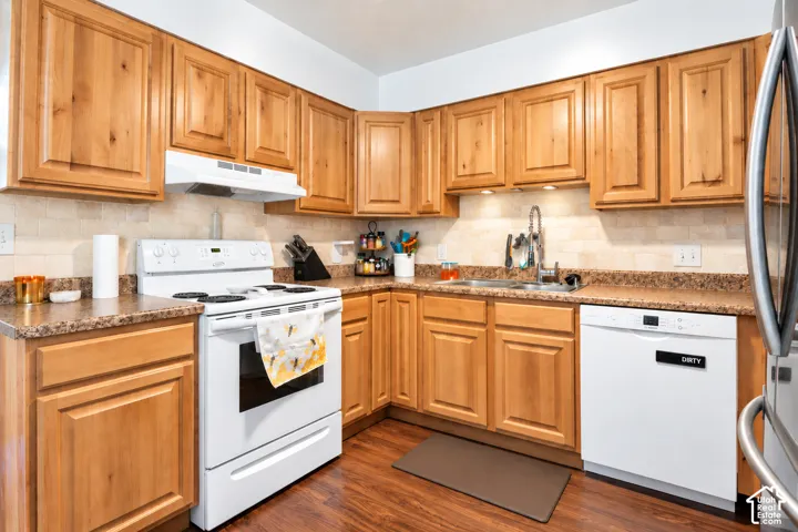 Kitchen featuring wood-finish cabinetry, solid surface countertops, a tile backsplash, and stainless steel appliances