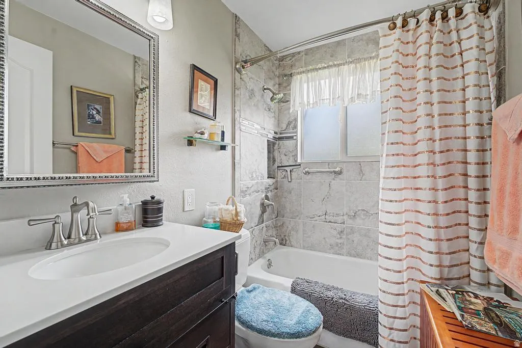 Vanity with a white countertop and undermount sink, brushed nickel faucet, framed mirror, and tiled shower surround with a bathtub